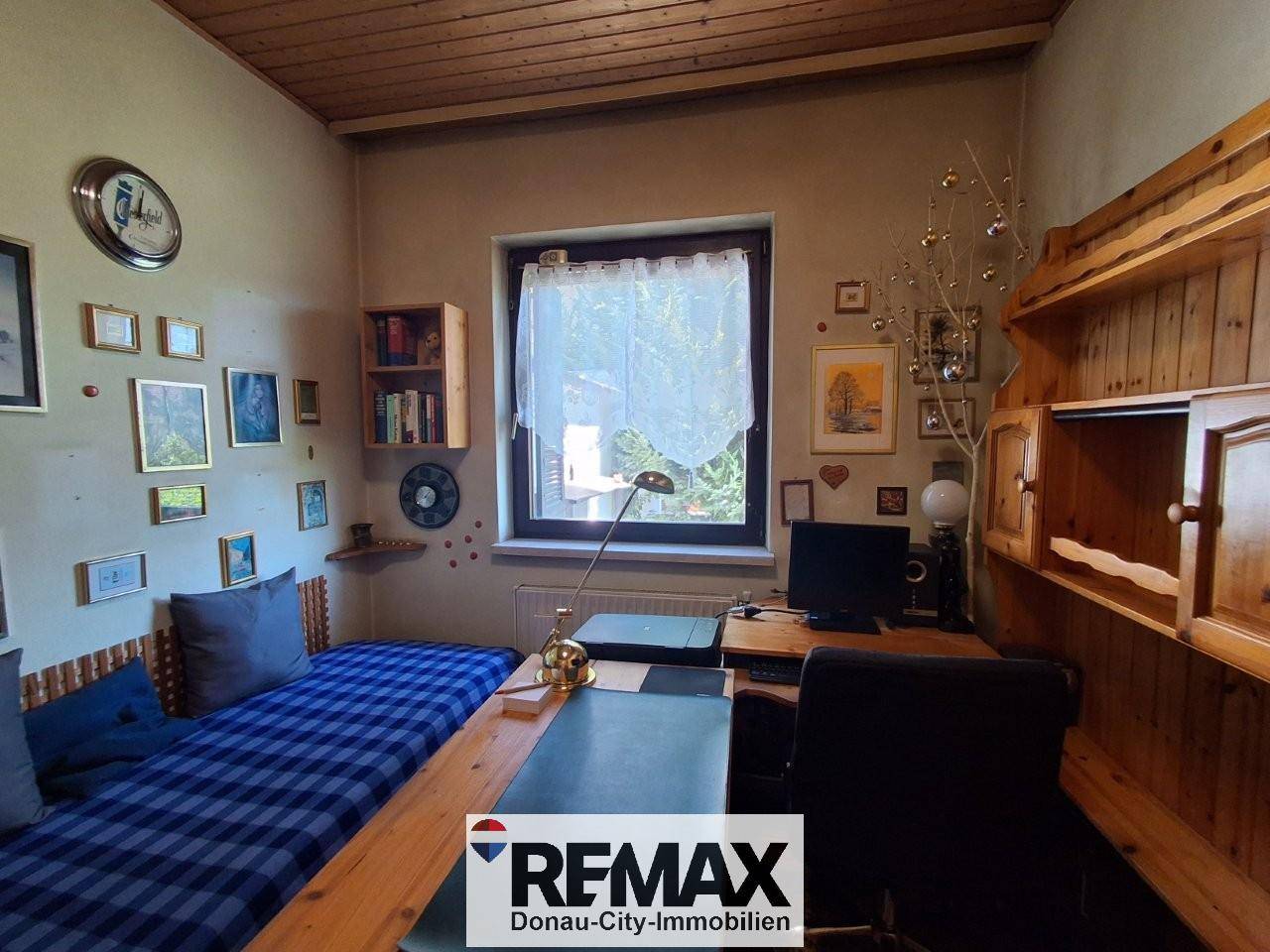 Helles Schlafzimmer mit Holzdecke, Einzelbett und integriertem Schreibtischbereich.