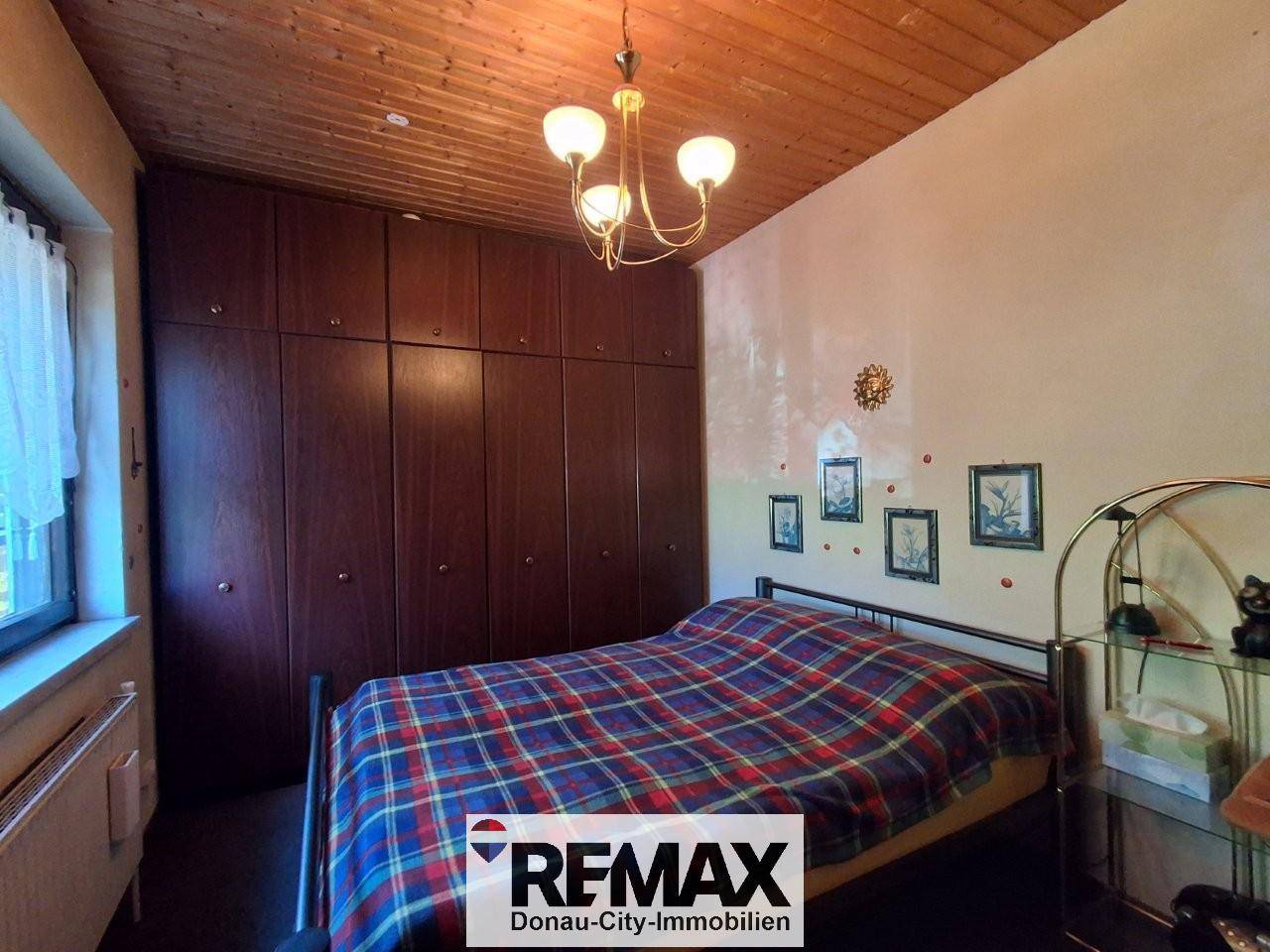 Schlafzimmer mit großem Kleiderschrank, Doppelbett und Holzdecke.