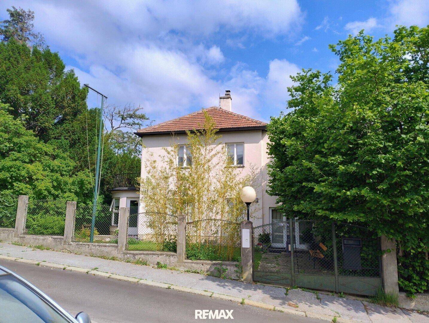 Historisches Einfamilienhaus mit Garten und grüner Umgebung an einer ruhigen Straße.