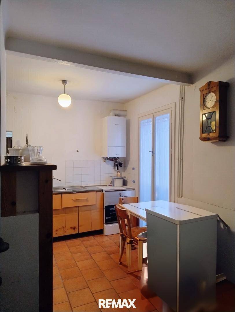 Kleine Küche mit Holzschränken, Terrakottafliesen und Gastherme an der Wand.