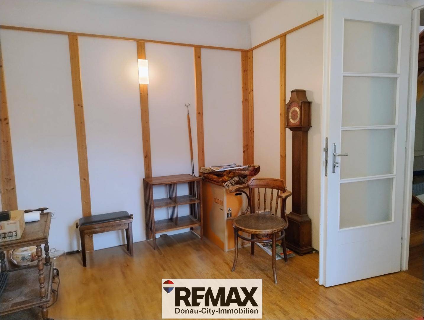 Raum mit Holzvertäfelung, traditionellen Möbeln und einer Standuhr, der als Durchgangszimmer dient.