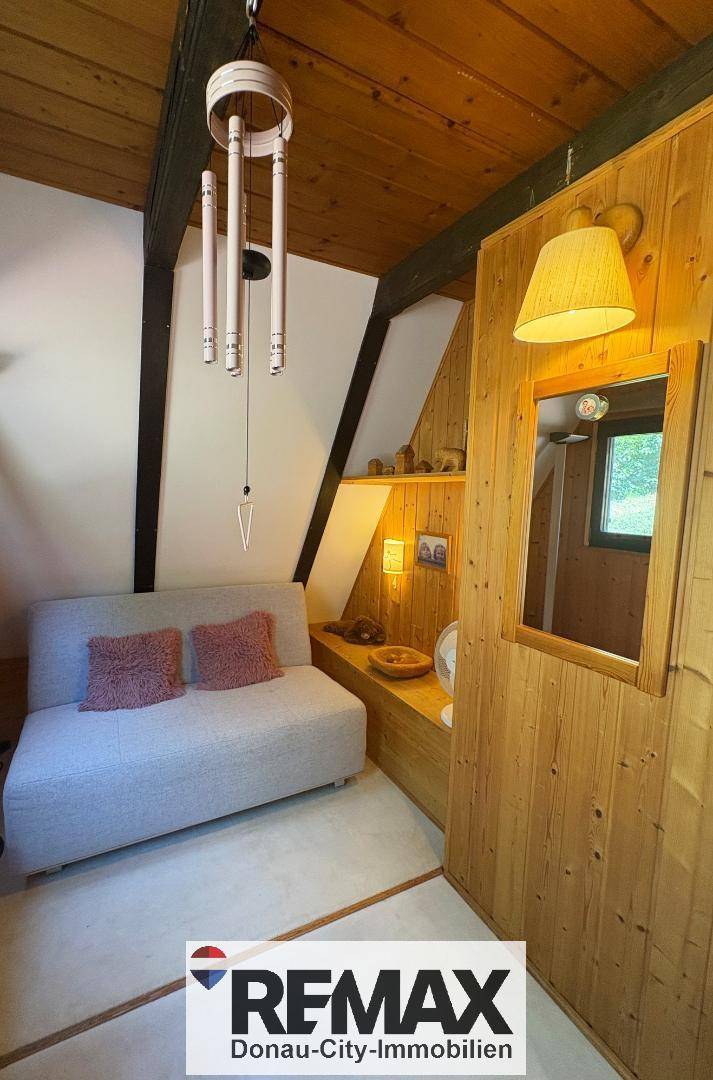 Kleiner, gemütlicher Bereich mit Holzwänden, Sofa und dekorativer Beleuchtung.