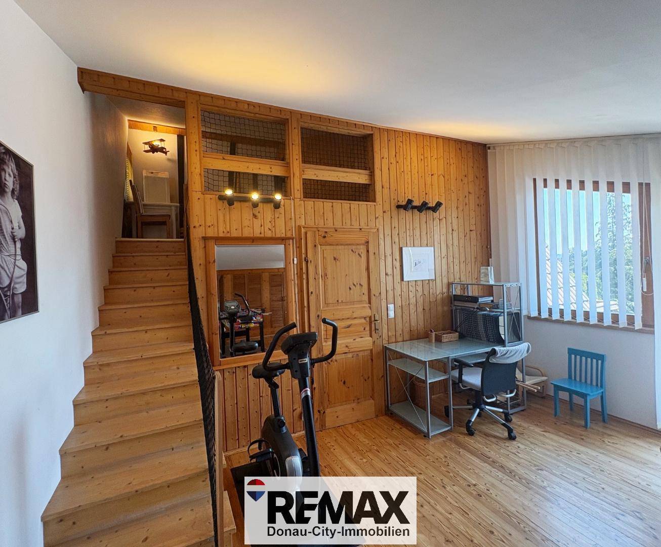 Flur mit Holzvertäfelung, Treppe und einem Bereich, der als Büro oder Fitnessraum genutzt werden kann.