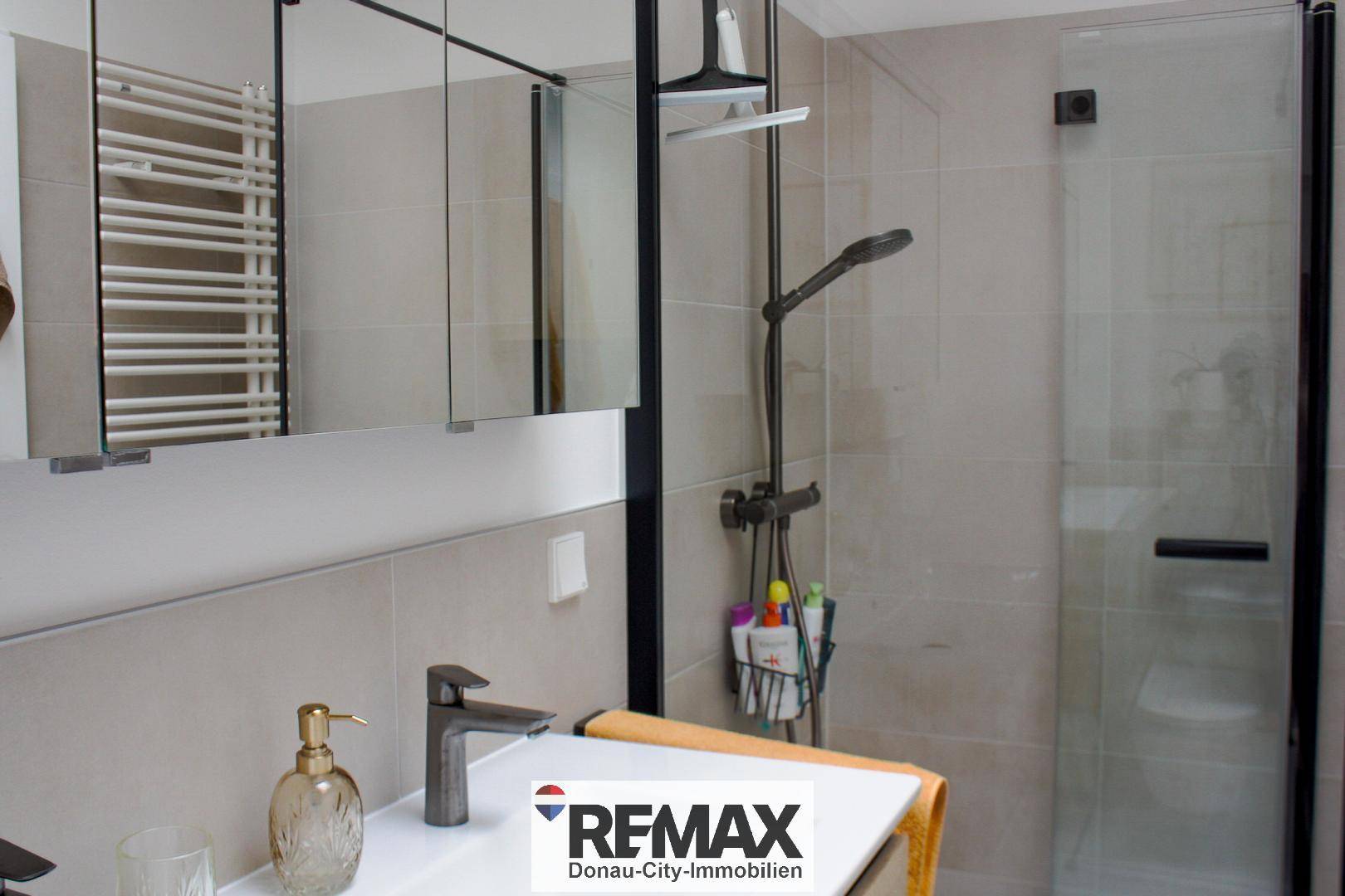 Modernes Badezimmer mit begehbarer Dusche, Einzelwaschbecken und beheiztem Handtuchhalter.