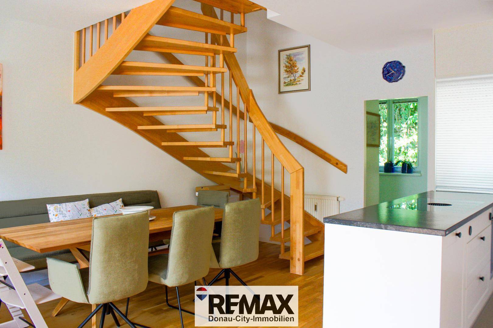 Essbereich mit Holztisch und Stühlen, direkt neben einer eleganten Holztreppe und der Küche.