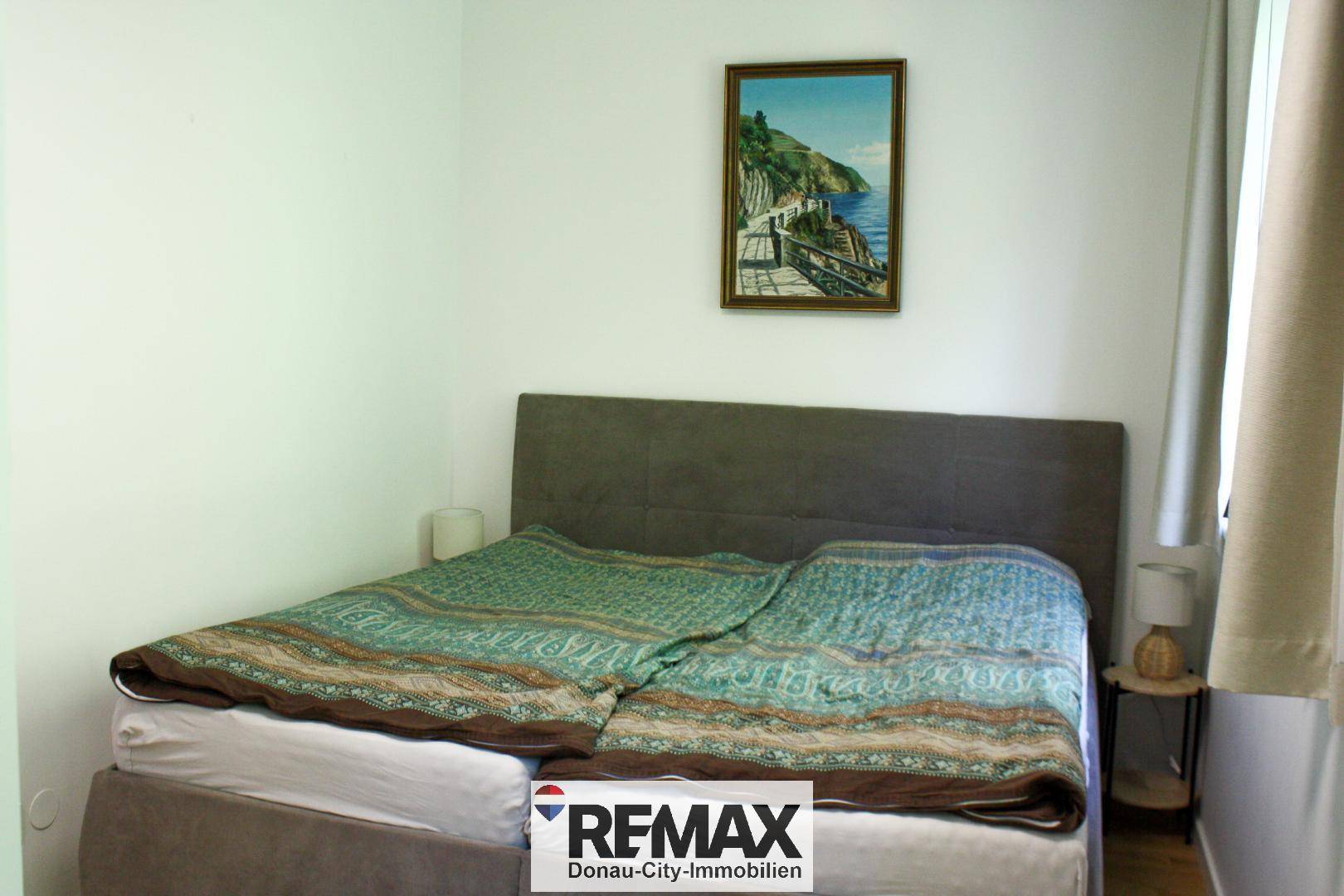 Schlafzimmer mit Doppelbett, schlichten Nachttischen und einem Wandbild, bietet Ruhe und Komfort.