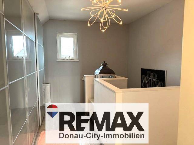 Heller Flur mit Einbauschränken, Fenster und moderner Deckenleuchte.
