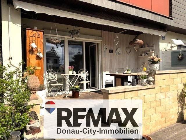 Gemütliche Terrasse mit Gartenmöbeln, Markise und dekorativen Elementen.