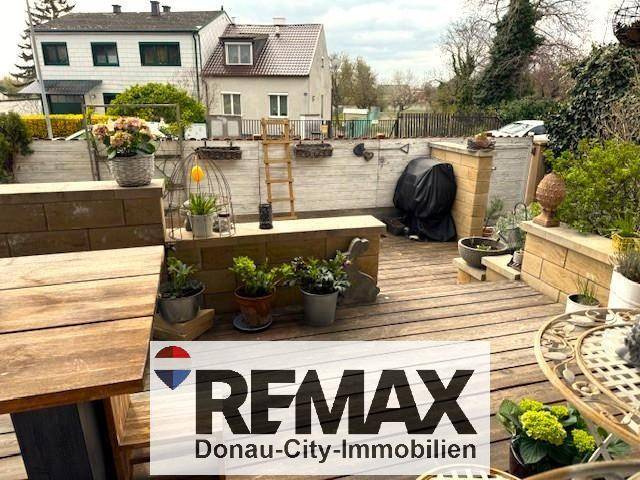Große Holzterrasse mit Grillbereich und Blick auf die umliegenden Häuser.