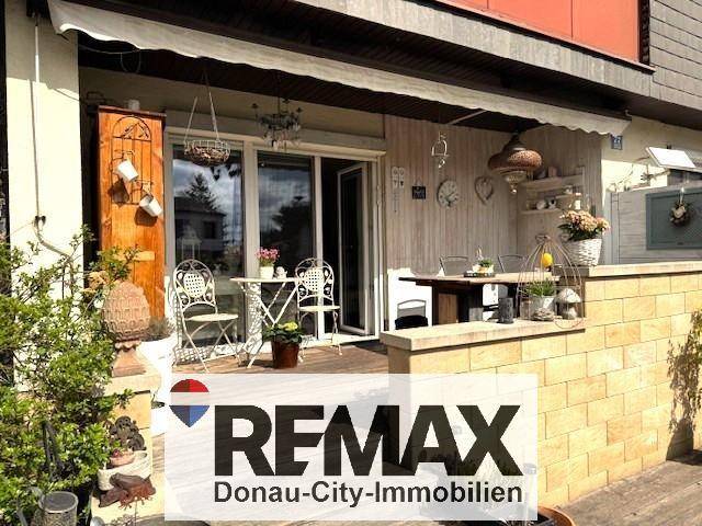 Gemütliche Terrasse mit Gartenmöbeln, Markise und dekorativen Elementen.