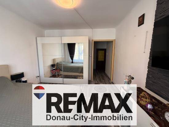 Schlafzimmer mit Doppelbett, großem Spiegelschrank und Zugang zum Flur.