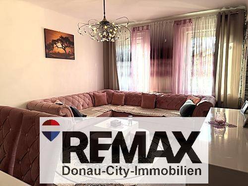 Gemütliches Wohnzimmer mit großem Ecksofa, Kronleuchter und Vorhängen an den Fenstern.