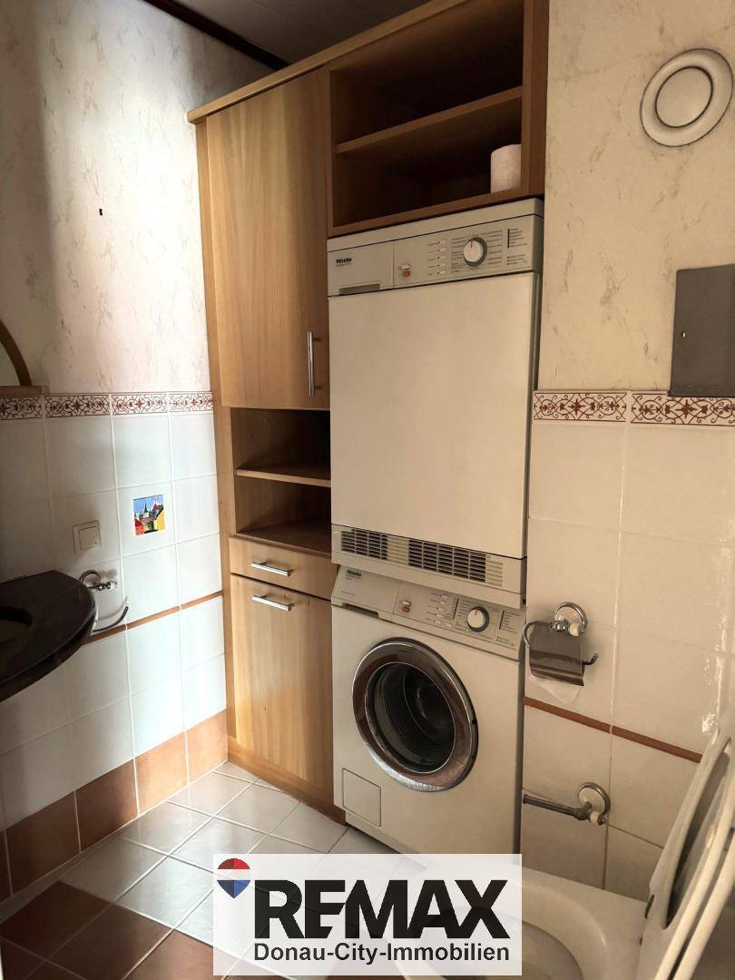 Kleines WC mit Waschmaschine und Trockner, praktisch eingerichtet mit Stauraum.