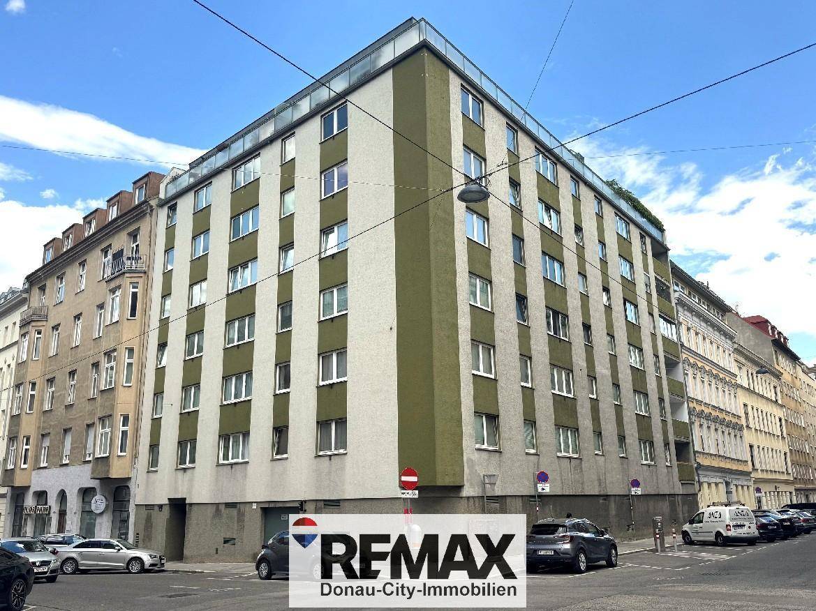 Mehrstöckiges Wohngebäude mit grüner und beiger Fassade an einer städtischen Straße.