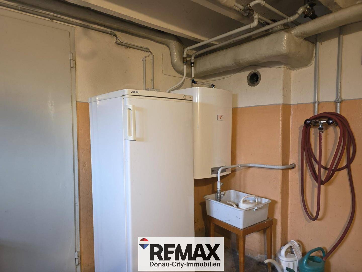 Hauswirtschaftsraum im Keller mit Boiler, Kühlschrank und Waschbecken.