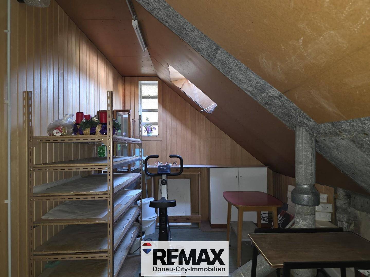 Dachboden als Abstellraum mit Regalen, Holzverkleidung und Dachfenster.