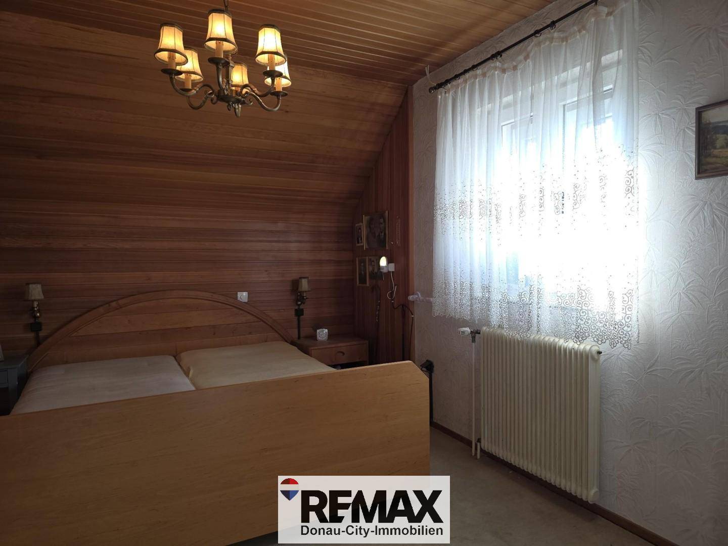 Schlafzimmer im Dachgeschoss mit Holzverkleidung, Doppelbett und Fenster.