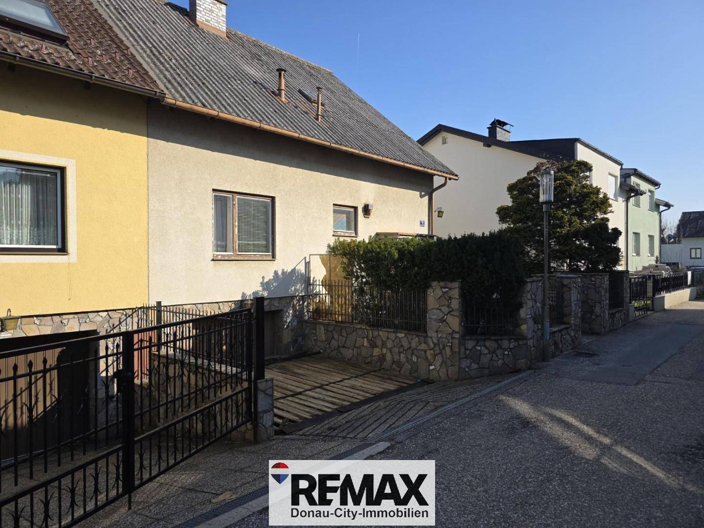 Ansicht des Hauses von der Straße mit Einfahrt zur Garage und gepflegter Hecke.