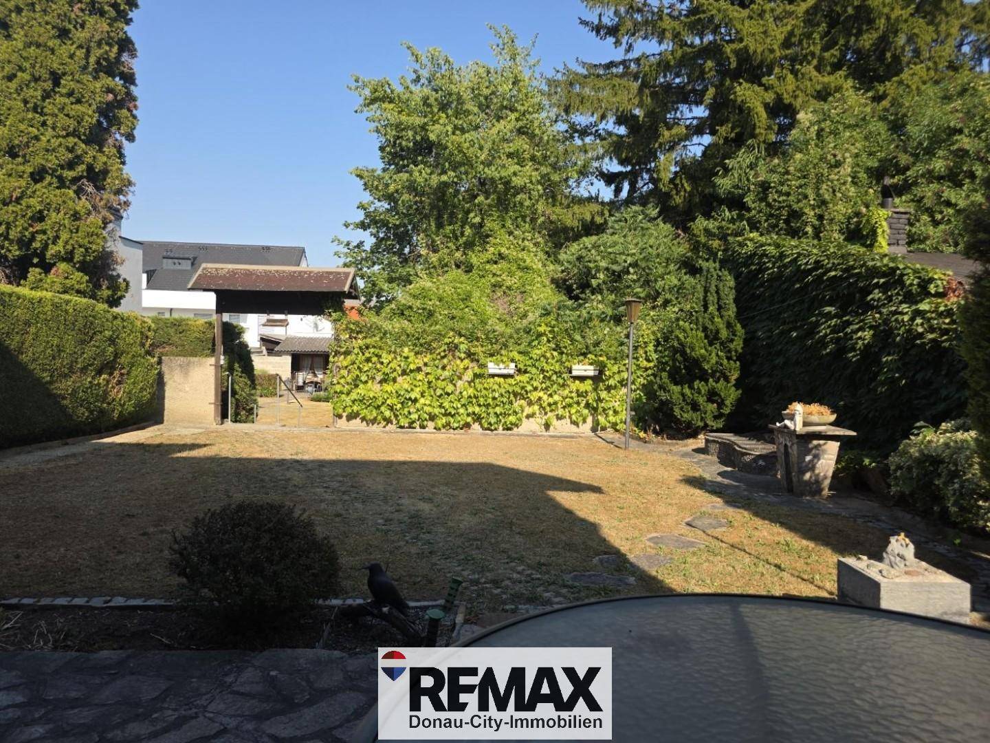 Großer, gepflegter Garten mit Rasenfläche, Bäumen und Sträuchern an einem sonnigen Tag.