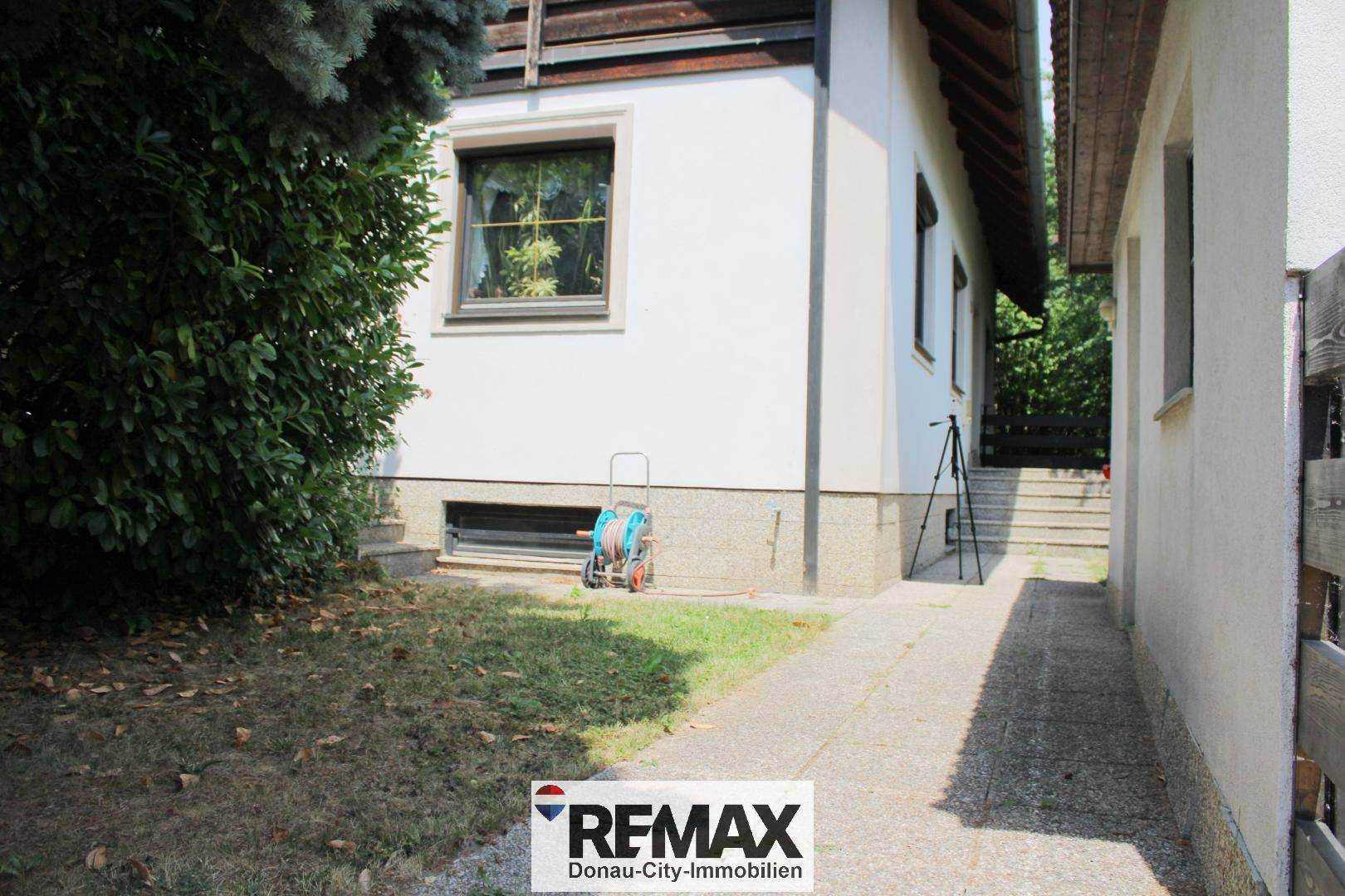 Seitenansicht des Hauses mit einem schmalen Weg und Zugang zum Gartenbereich.