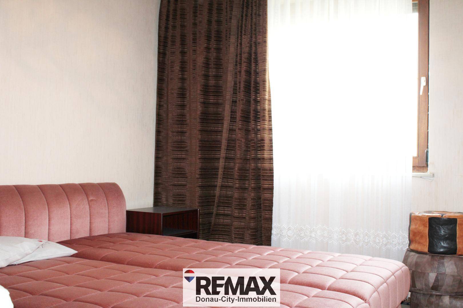 Schlafzimmer mit Doppelbett, Nachttisch und dunklen Vorhängen, die für Privatsphäre sorgen.