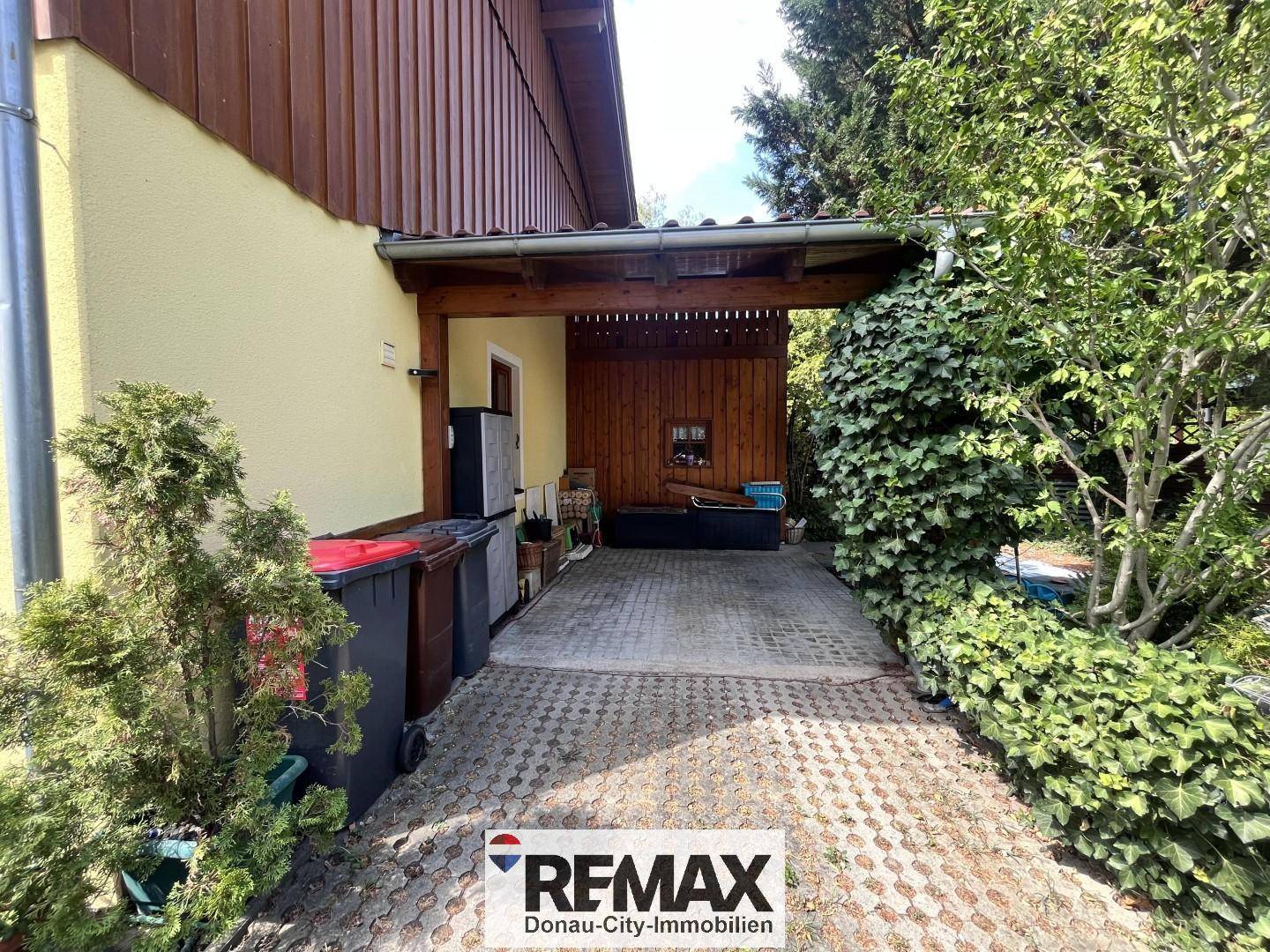Überdachter Stellplatz oder Carport mit gepflastertem Boden und Abstellmöglichkeiten.