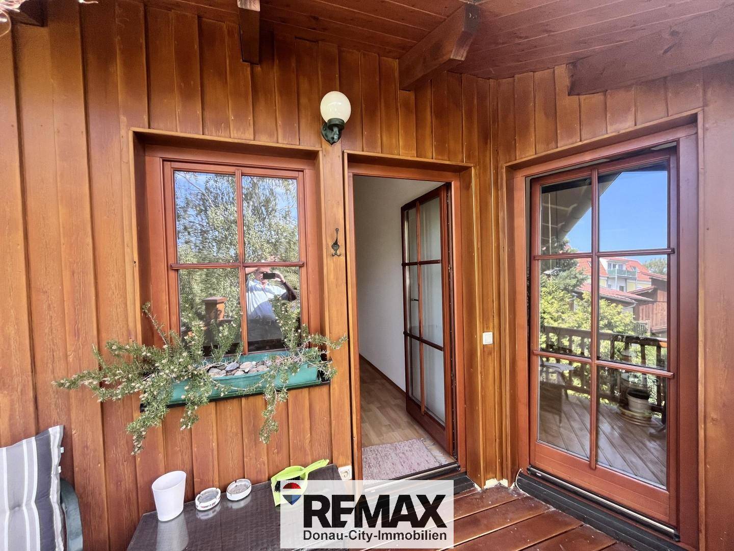 Kleiner Holzbalkon mit Blumenkasten und Zugang zum Innenbereich.