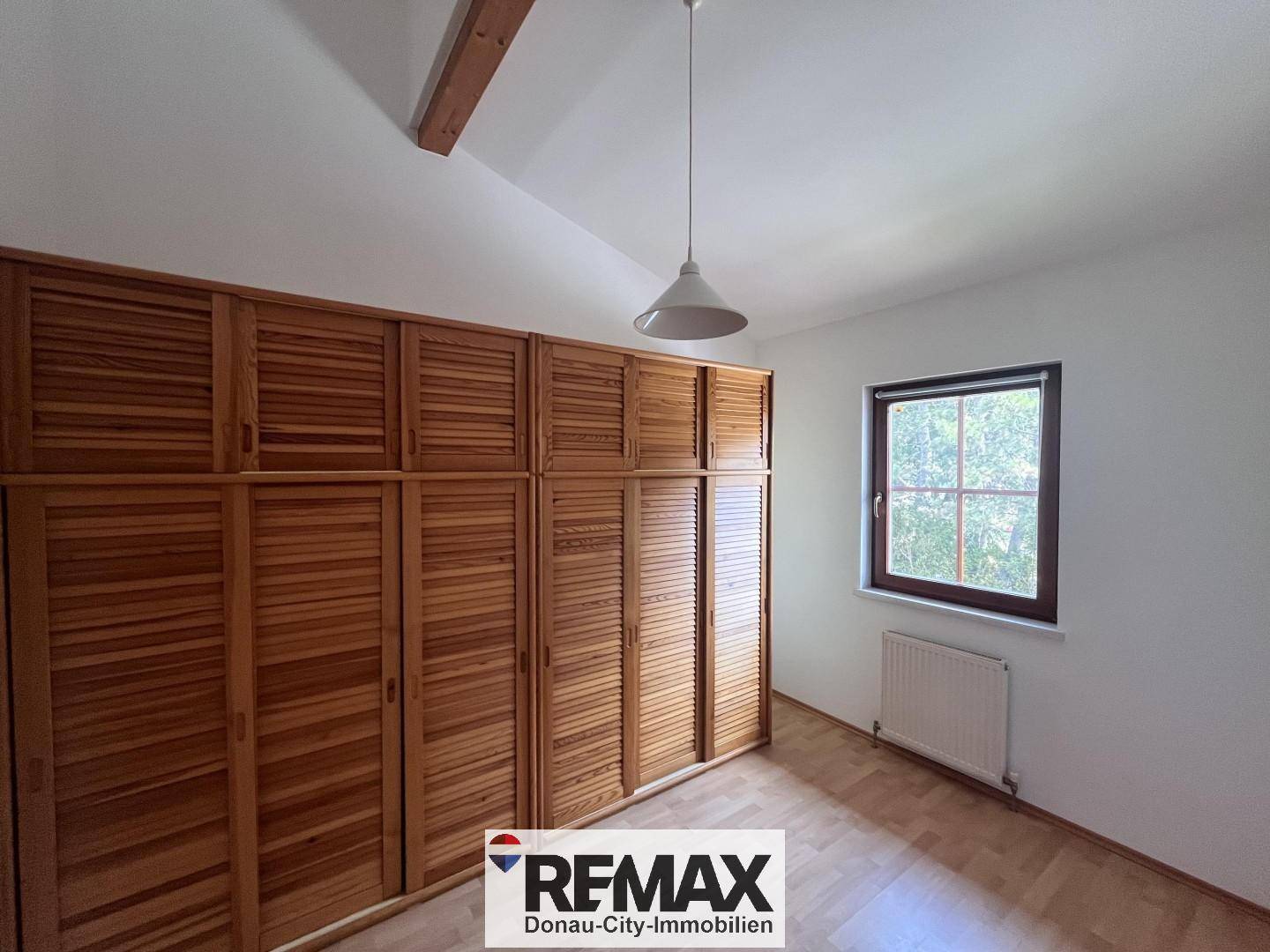 Schlafzimmer mit geräumigen Einbauschränken aus Holz und hellem Boden.