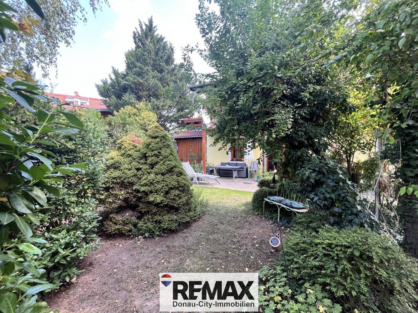 Weitläufiger Garten mit verschiedenen Pflanzen und Blick auf die Terrasse des Hauses.