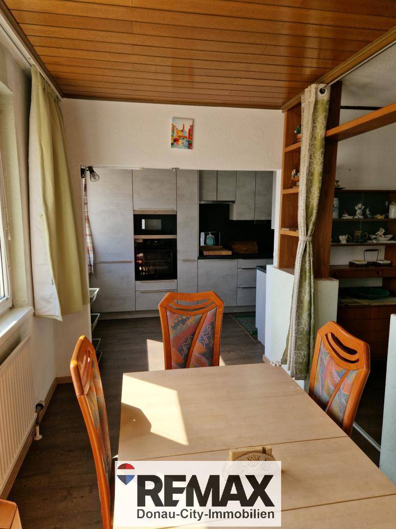 Essbereich mit Holztisch und Stühlen, angrenzend an die moderne Küche mit Holzdecke.