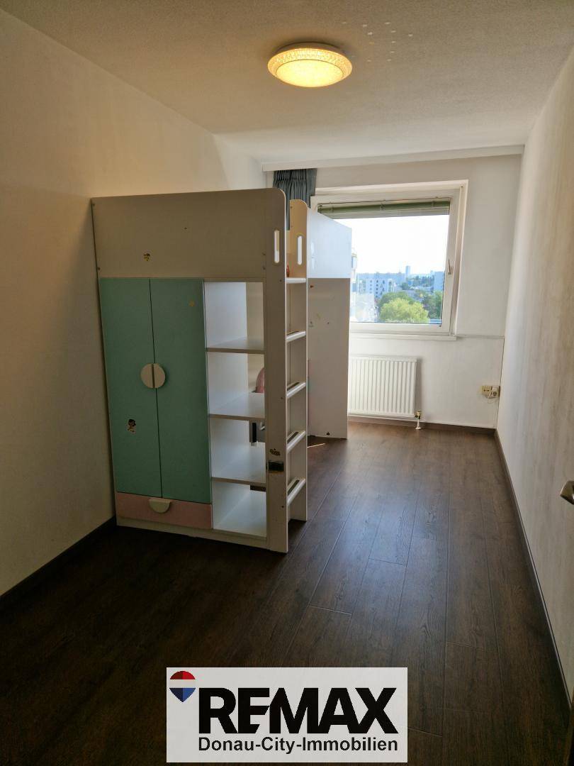 Kinderzimmer mit Hochbett, Fenster und dunklem Laminatboden, hell und funktional eingerichtet.