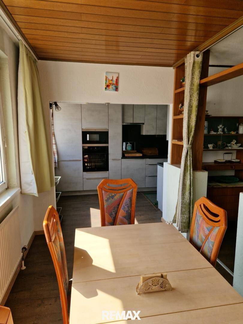 Essbereich mit Holztisch und Stühlen, angrenzend an die Küche, mit Holzdecke und Fenster.