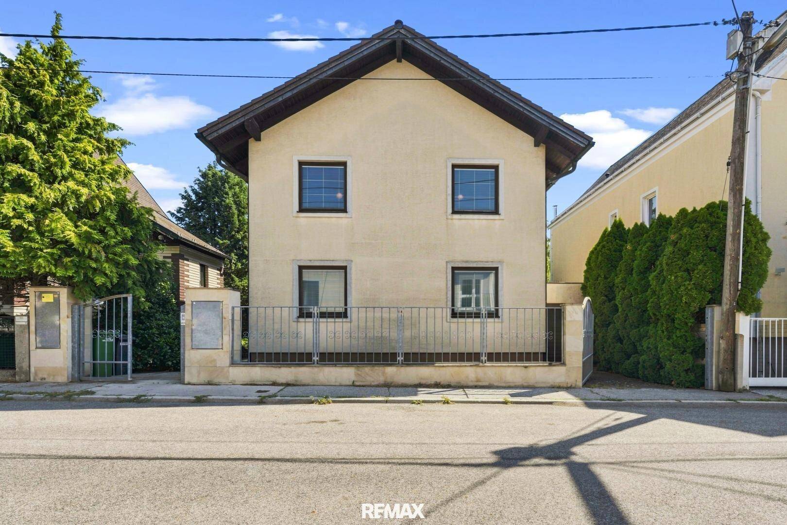Ansicht des Einfamilienhauses von der Straße mit Vorgarten und Zaun.