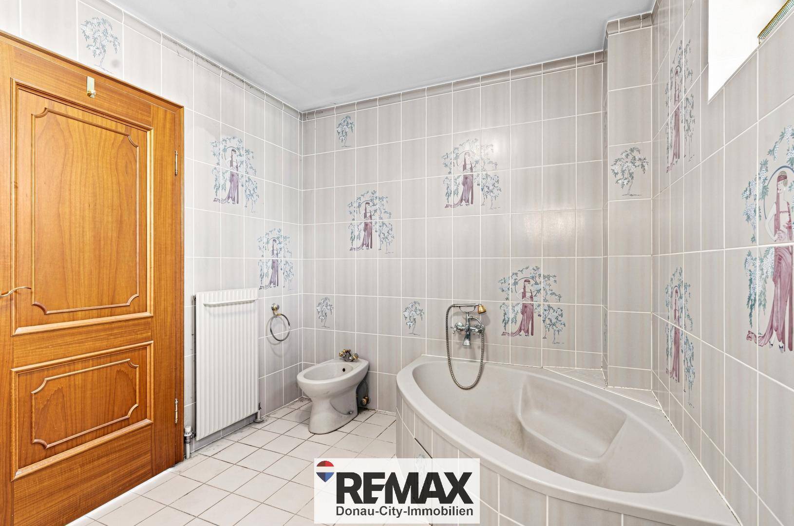 Badezimmer mit Badewanne, Bidet und Fliesenboden.