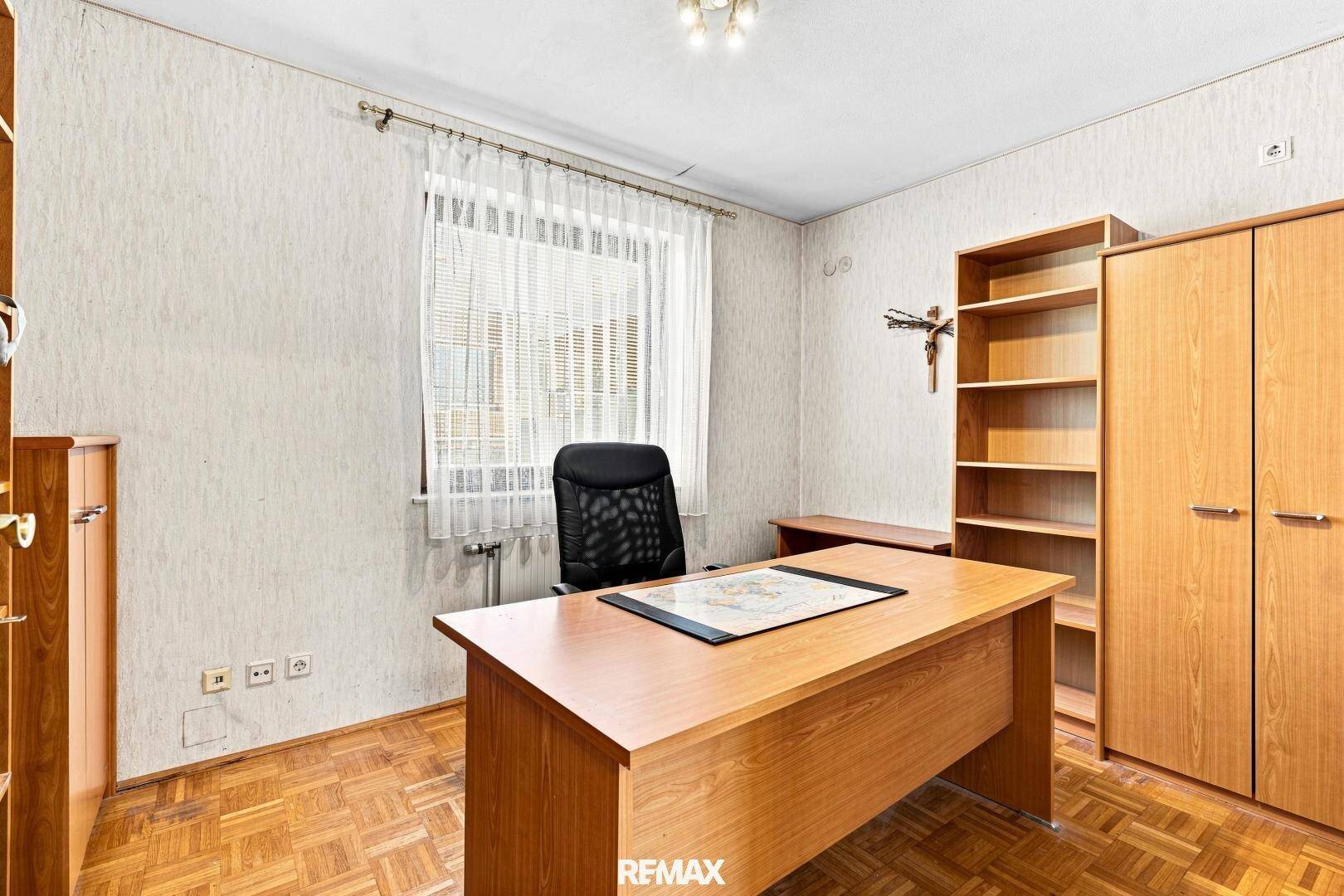 Arbeitszimmer mit Holzschreibtisch, Regalen und einem Fenster für natürliches Licht.