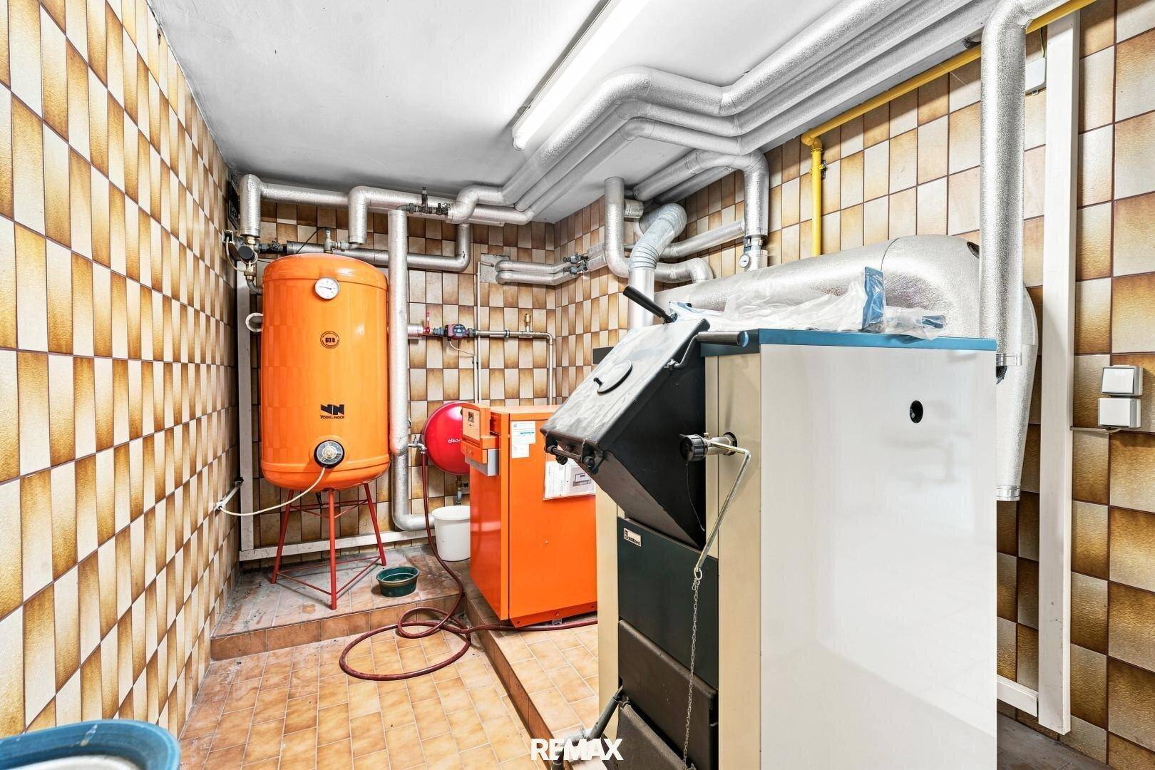 Heizungsraum mit Kessel, Warmwasserspeicher und sichtbaren Rohrleitungen.