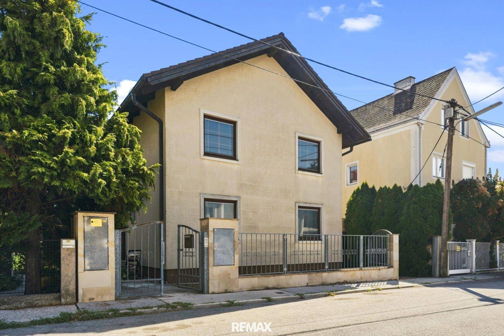 Vorderansicht des Einfamilienhauses von der Straße aus mit Zaun und Eingangsbereich.