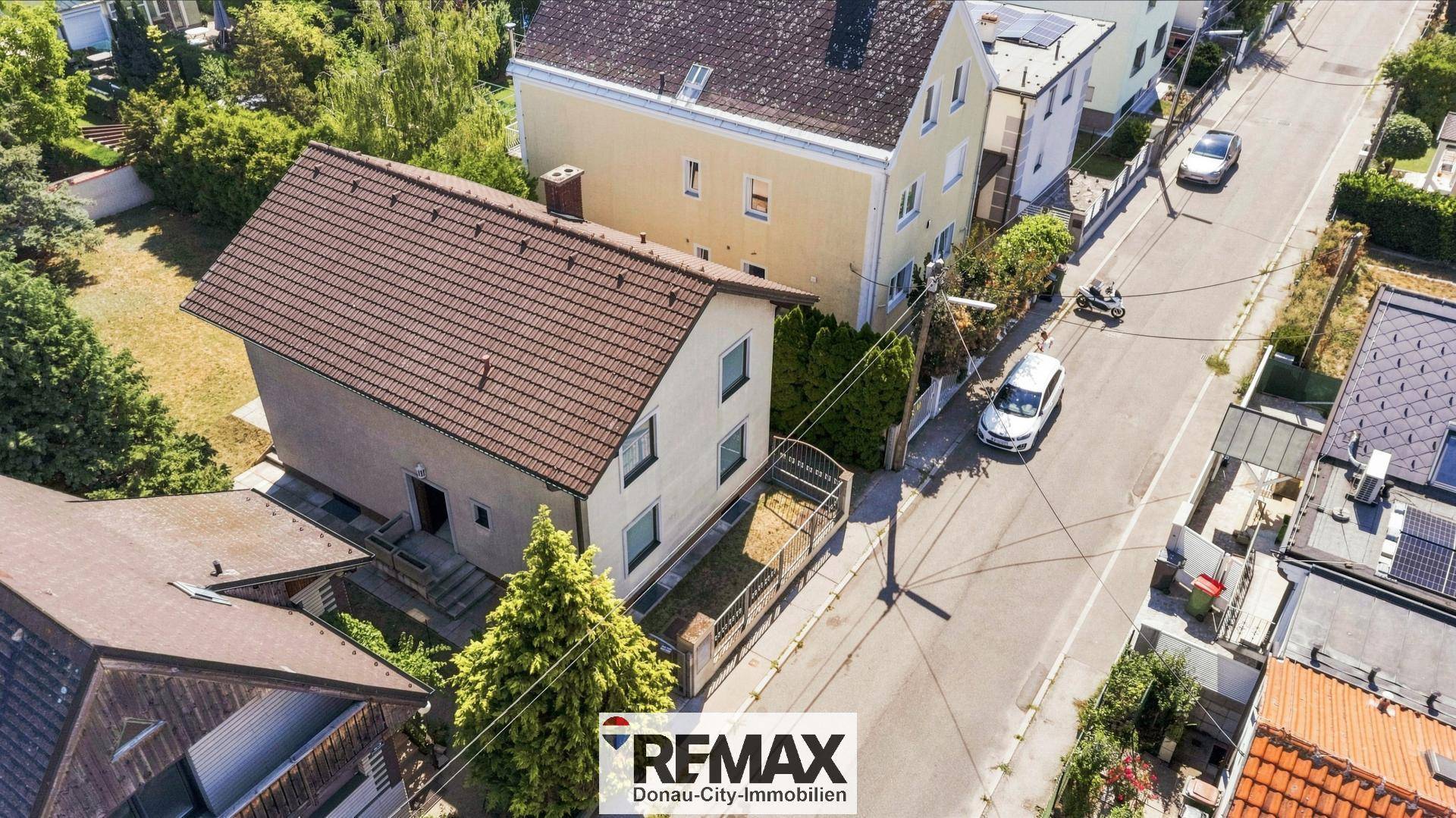 Luftaufnahme des Hauses und der umliegenden Nachbarschaft mit Straße und weiteren Gebäuden.
