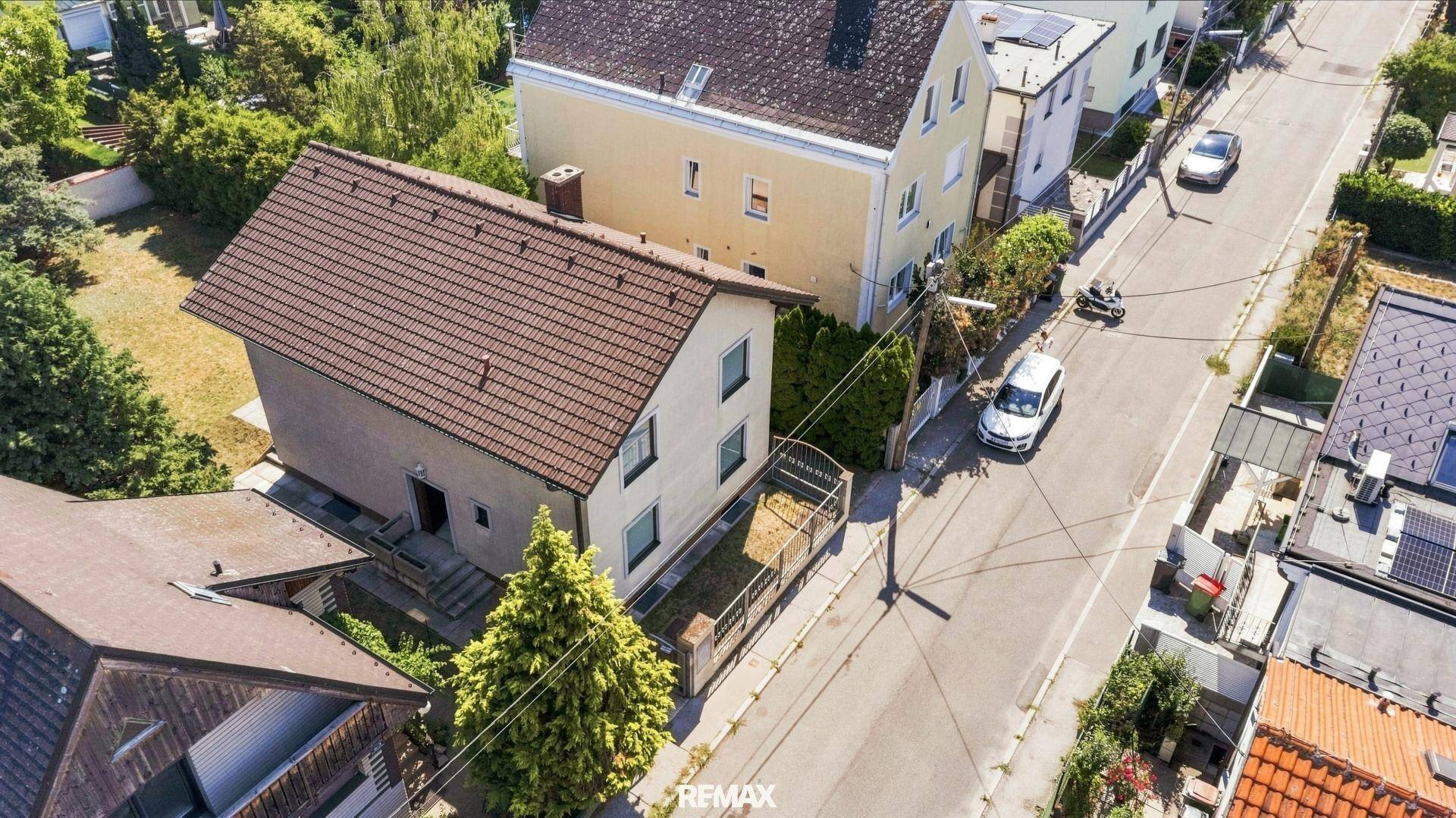 Luftaufnahme des Hauses und der umliegenden Nachbarschaft mit Straße und weiteren Gebäuden.