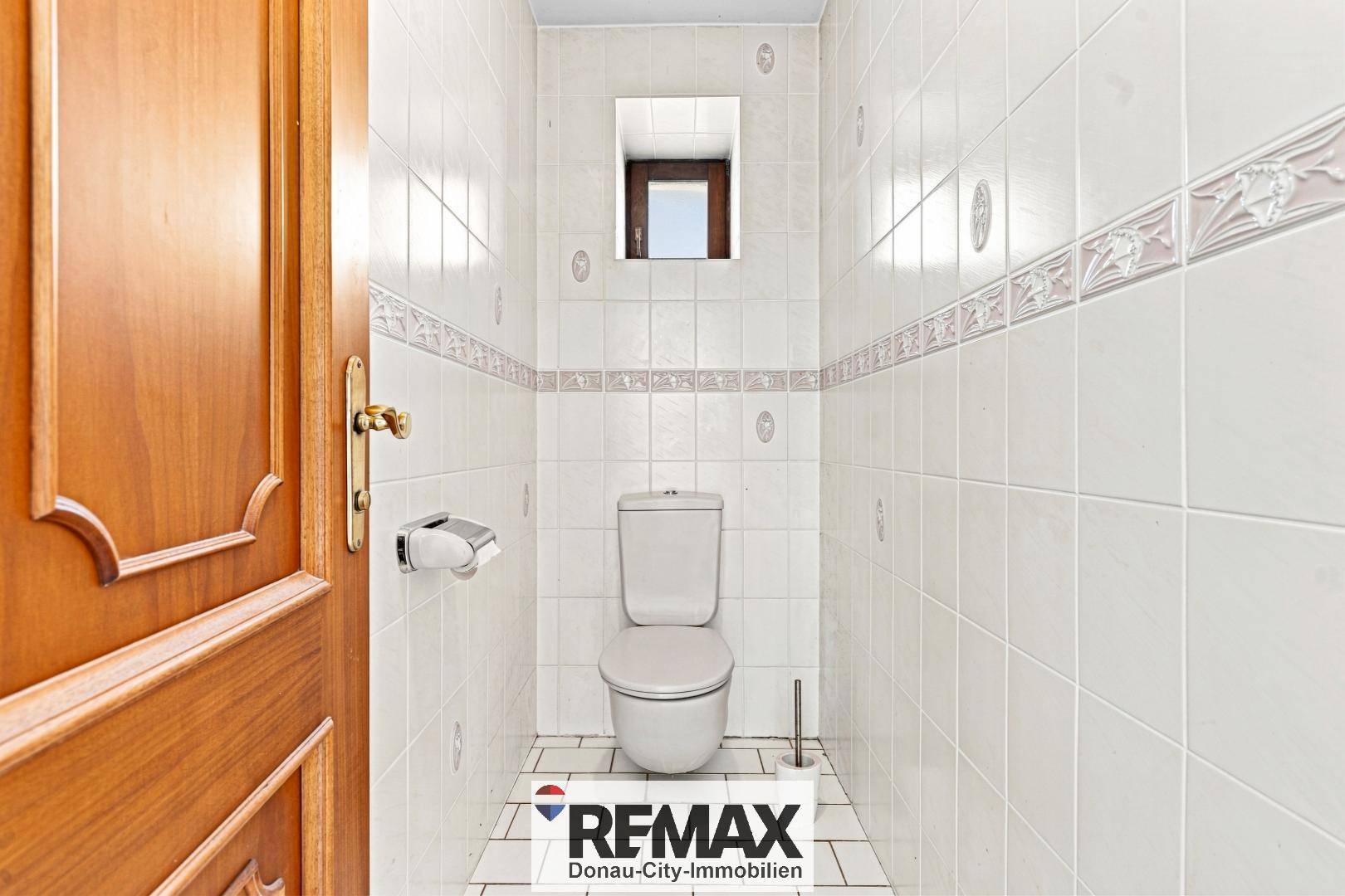 Separates WC mit Toilette, Waschbecken und Fliesenboden.