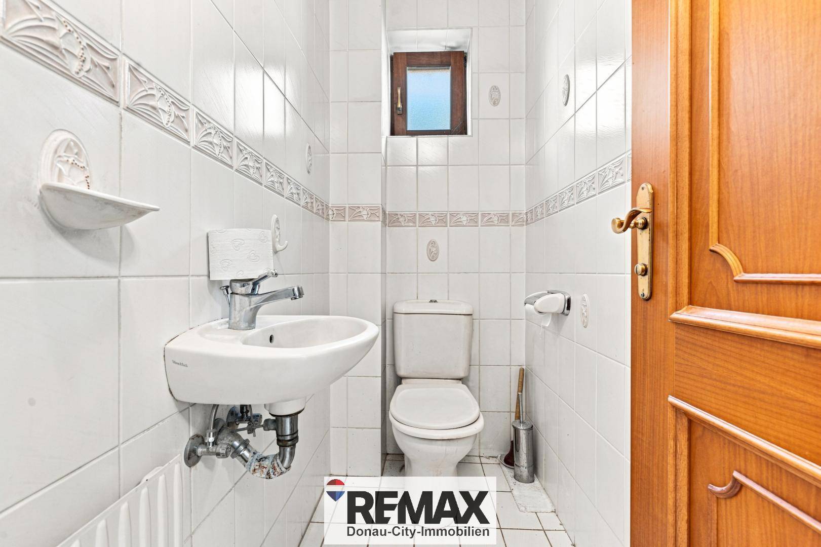 Separates WC mit Waschbecken, Toilette und Fliesenboden.