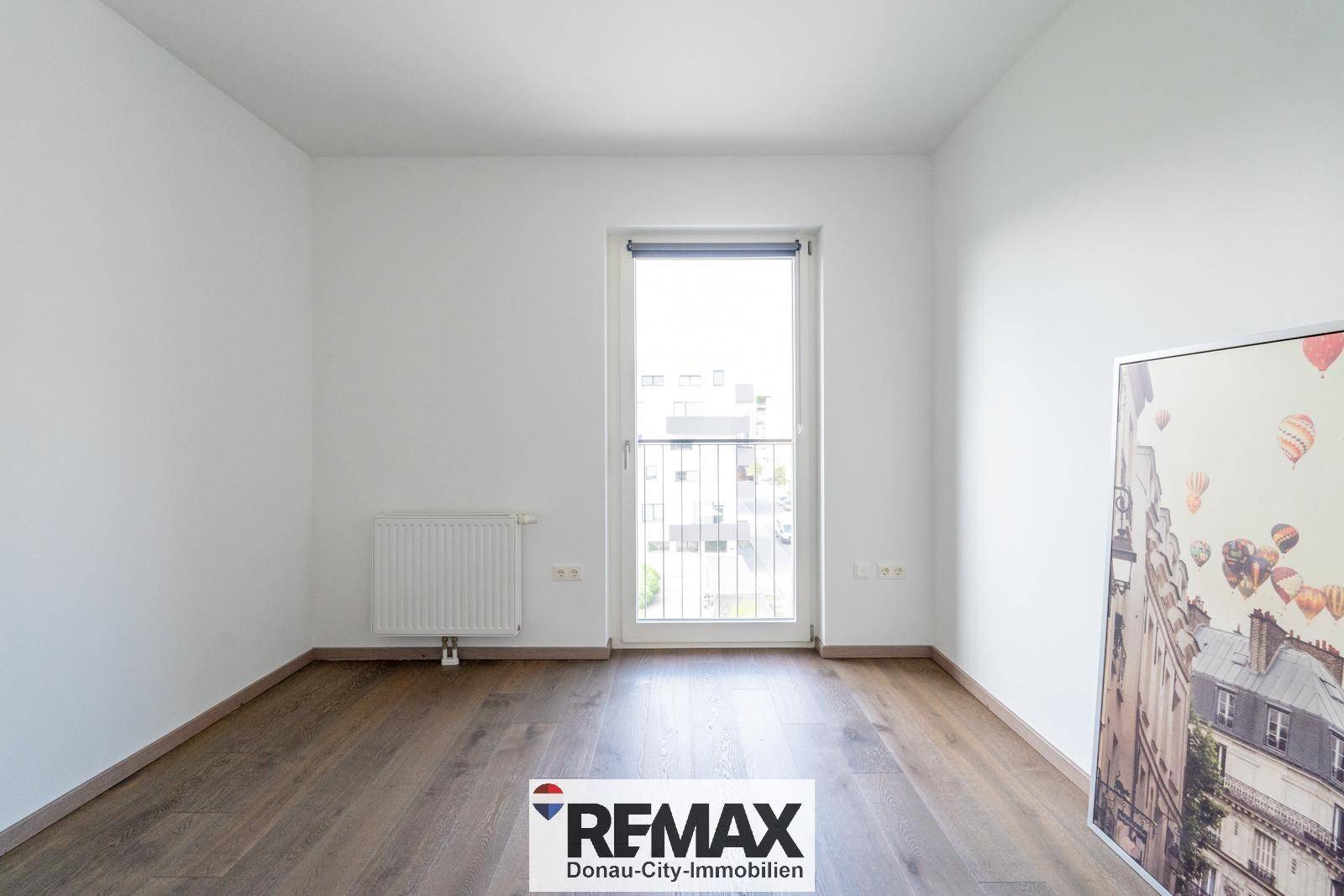 Ruhiges Schlafzimmer mit Holzboden und großem Fenster, das viel Tageslicht hereinlässt.