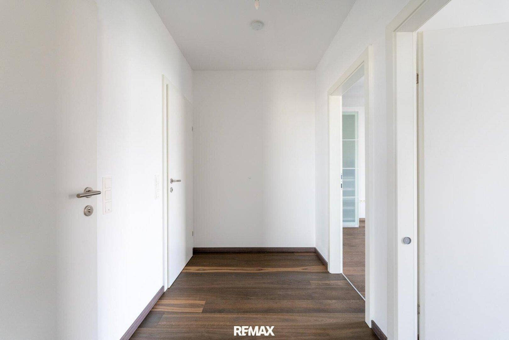 Heller Flur mit dunklem Holzboden, der zu den verschiedenen Räumen der Wohnung führt.