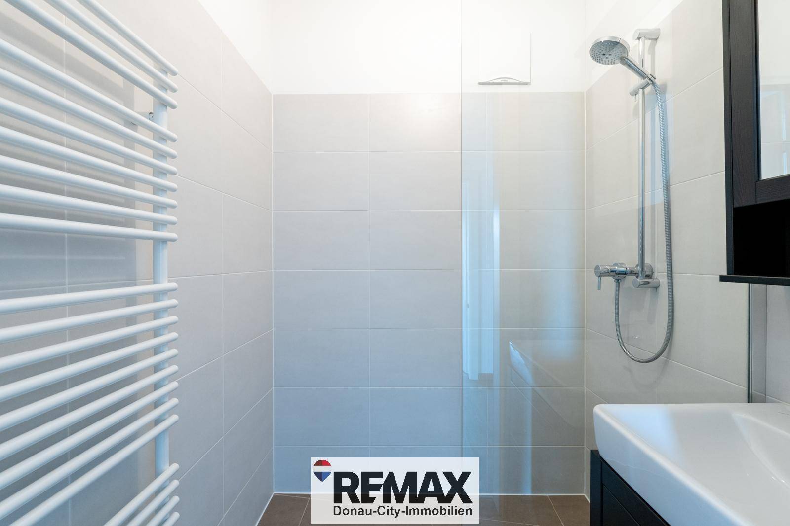 Moderne Duschkabine mit Glasabtrennung und hellen Fliesen im Badezimmer.
