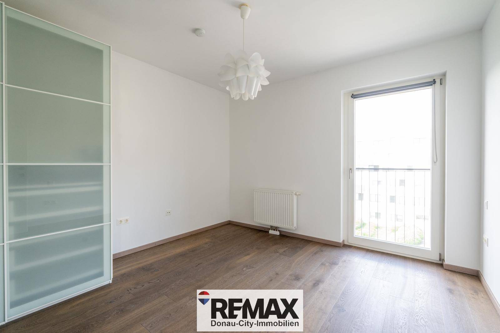 Helles Schlafzimmer mit Holzboden, großem Fenster und modernem Kleiderschrank.