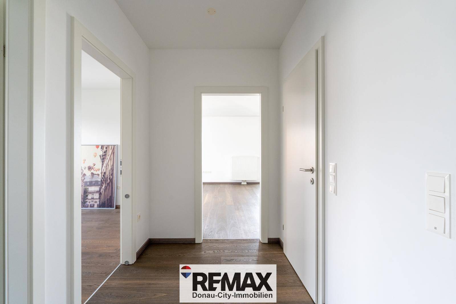 Geräumiger Flur mit Holzboden und offenen Türen, die den Blick in angrenzende Zimmer freigeben.