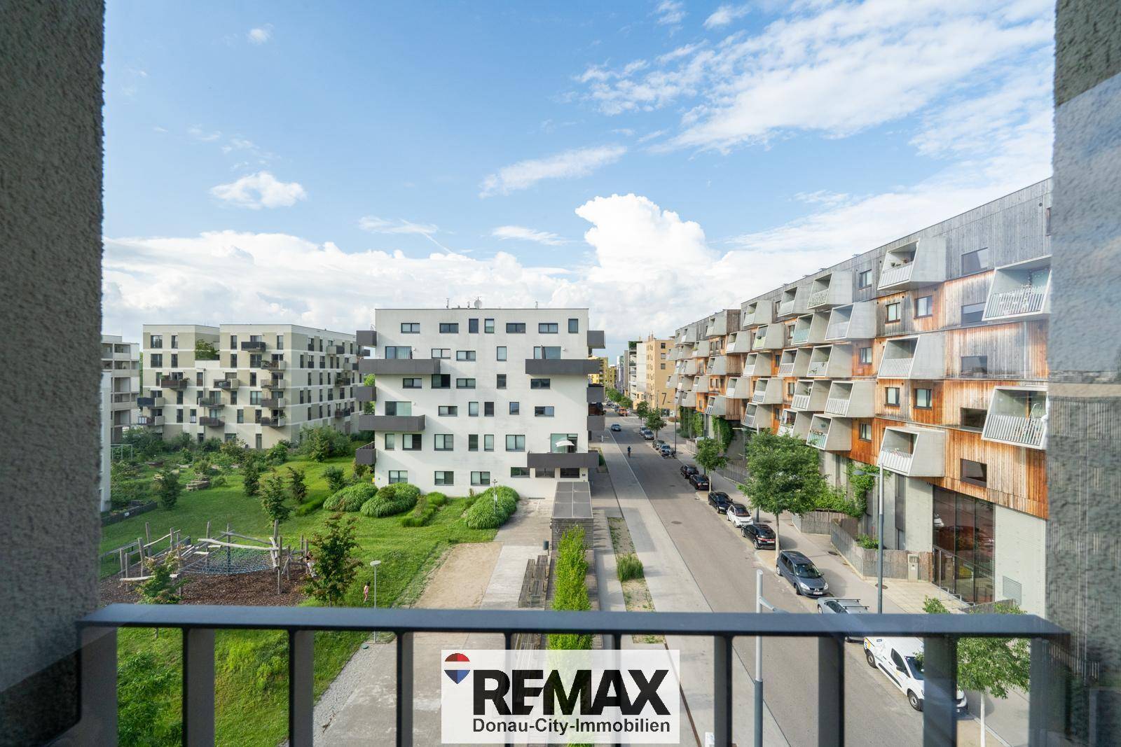 Blick vom Balkon auf die moderne Wohnsiedlung mit Grünflächen und Straße.