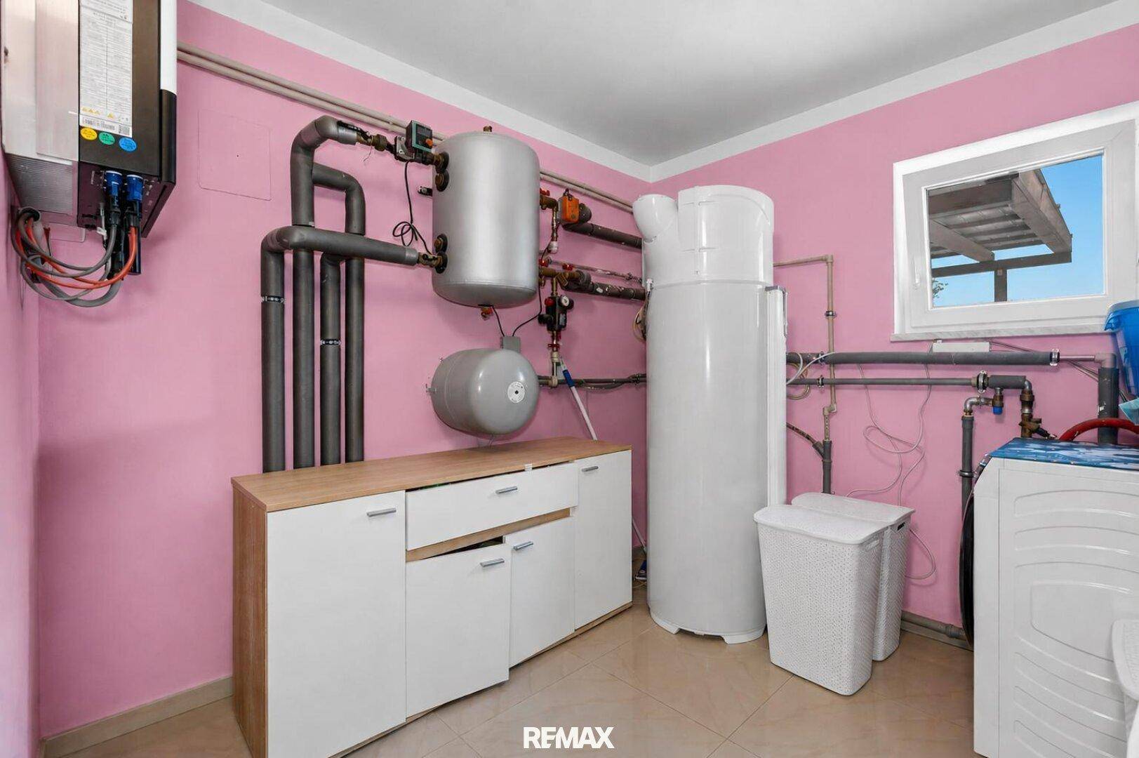 Hauswirtschaftsraum mit Heizungsanlage, Waschmaschine und rosa gestrichenen Wänden.