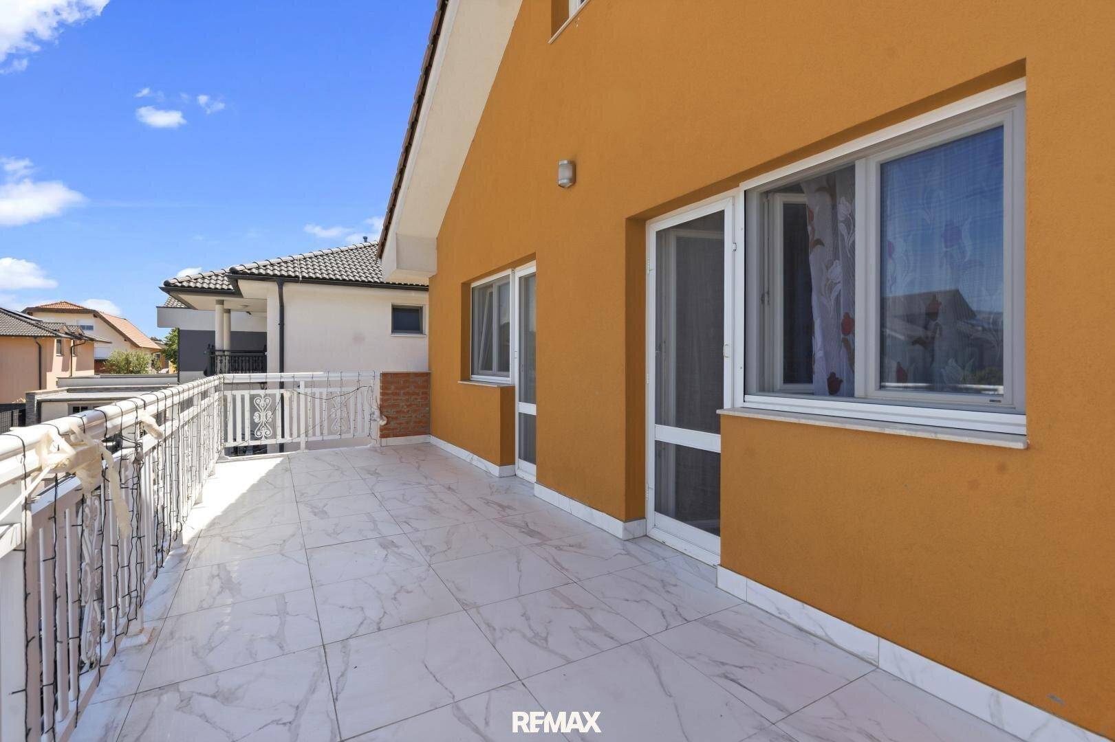 Großer Balkon mit Fliesenboden und weißem Geländer, ideal für Entspannung im Freien.