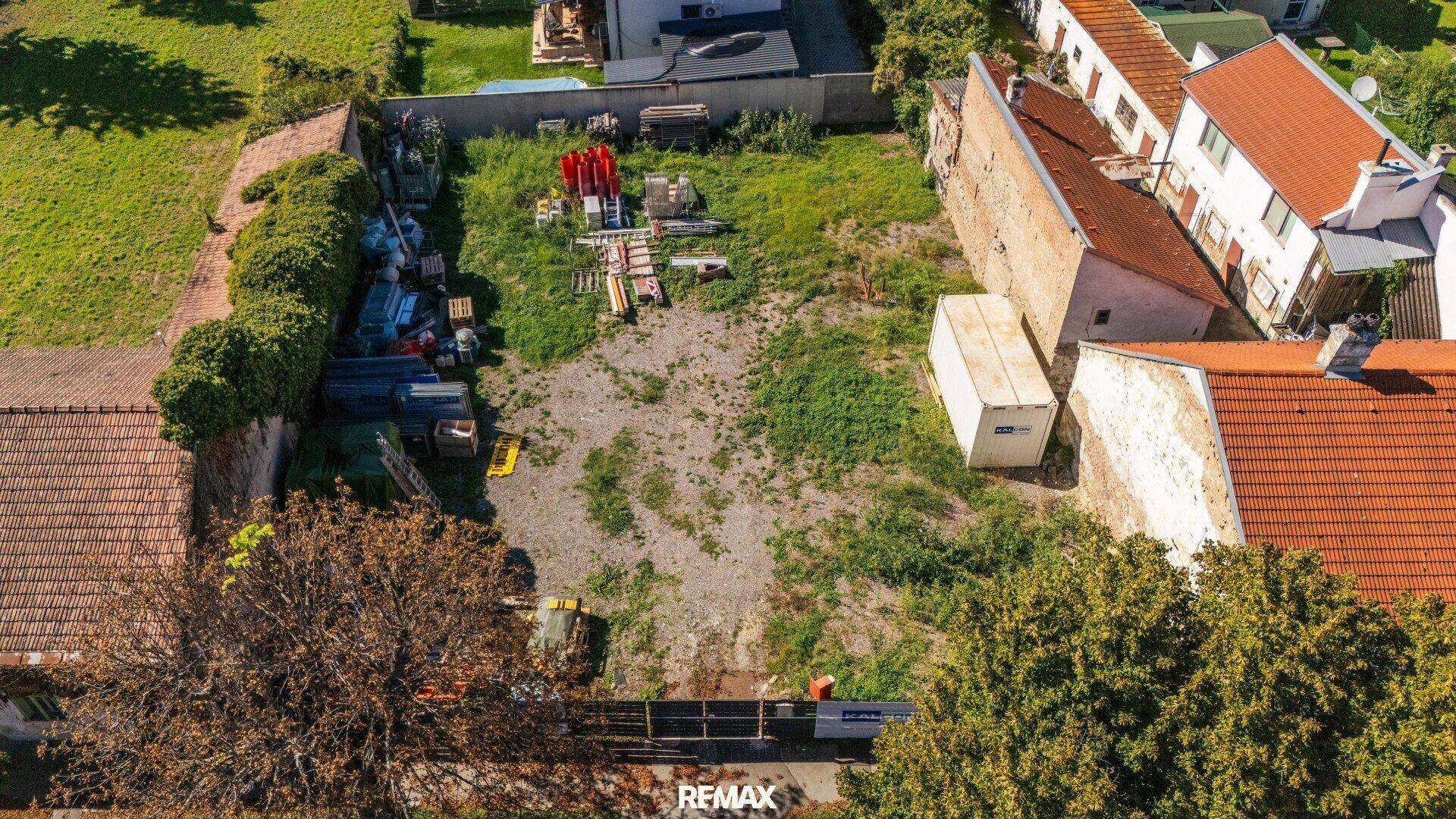 Detaillierte Luftaufnahme des unbebauten Grundstücks mit Gras und gelagerten Gegenständen.